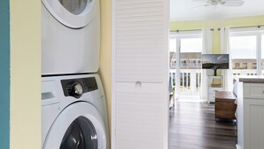 Uma lavanderia com máquina de lavar, secadora e ventilador de teto.