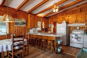 Ein Holzblockhaus-Interieur mit Küche, Essbereich und Barhocker.