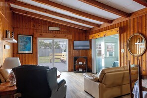 Ein gemütliches Blockhaus-Interieur mit Holzwänden, einem Fernseher, einer Karte und einer Bank draußen.