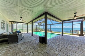 Ein Innenpoolbereich mit Blick auf den Ozean, einem Deckenventilator und einer Sitzecke mit Teppich.