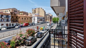 Un balcone con vista su una strada trafficata, edifici e cielo sereno.