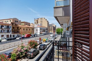 A balcony with a view of a busy street, buildings, and a clear sky. - Myla's Rooms 2 with Balcony, Wi-Fi and Air Conditioning (Palermo)