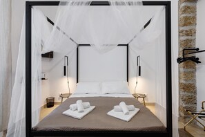 A bed with a canopy, two bedside tables, a wall-mounted towel rack, and a stone accent wall. - Myla's Rooms 2 with Balcony, Wi-Fi and Air Conditioning (Palermo)