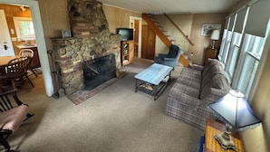 Una sala de estar con chimenea de piedra, un sofá, una mesa de centro y un televisor.
