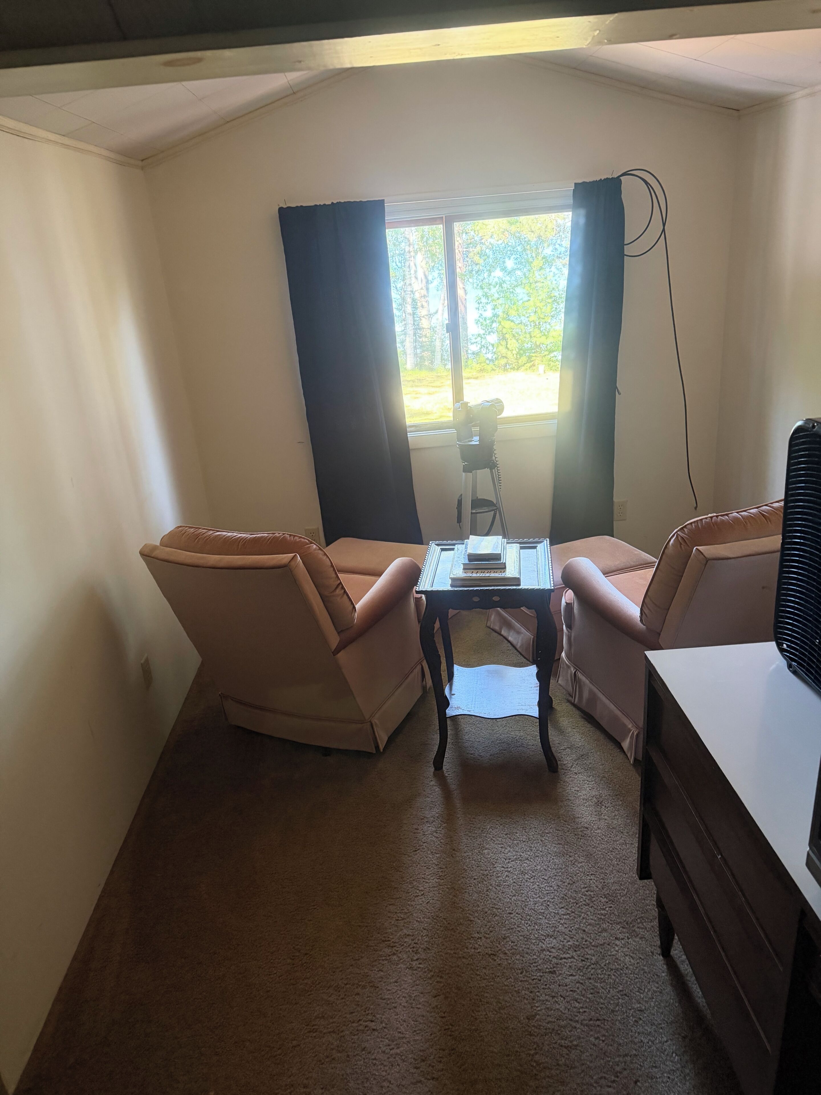 A room with two armchairs, a small table, and a window with curtains.