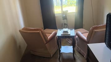 A room with two armchairs, a small table, and a window with curtains.