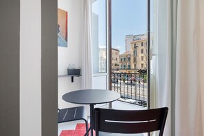 Un balcone con tavolo e sedie, vista su edifici e ringhiera.