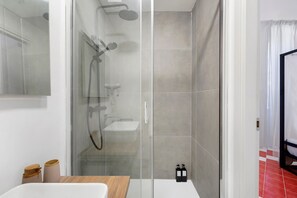 Un bagno moderno con cabina doccia in vetro, mobile lavabo in legno e lavandino bianco.