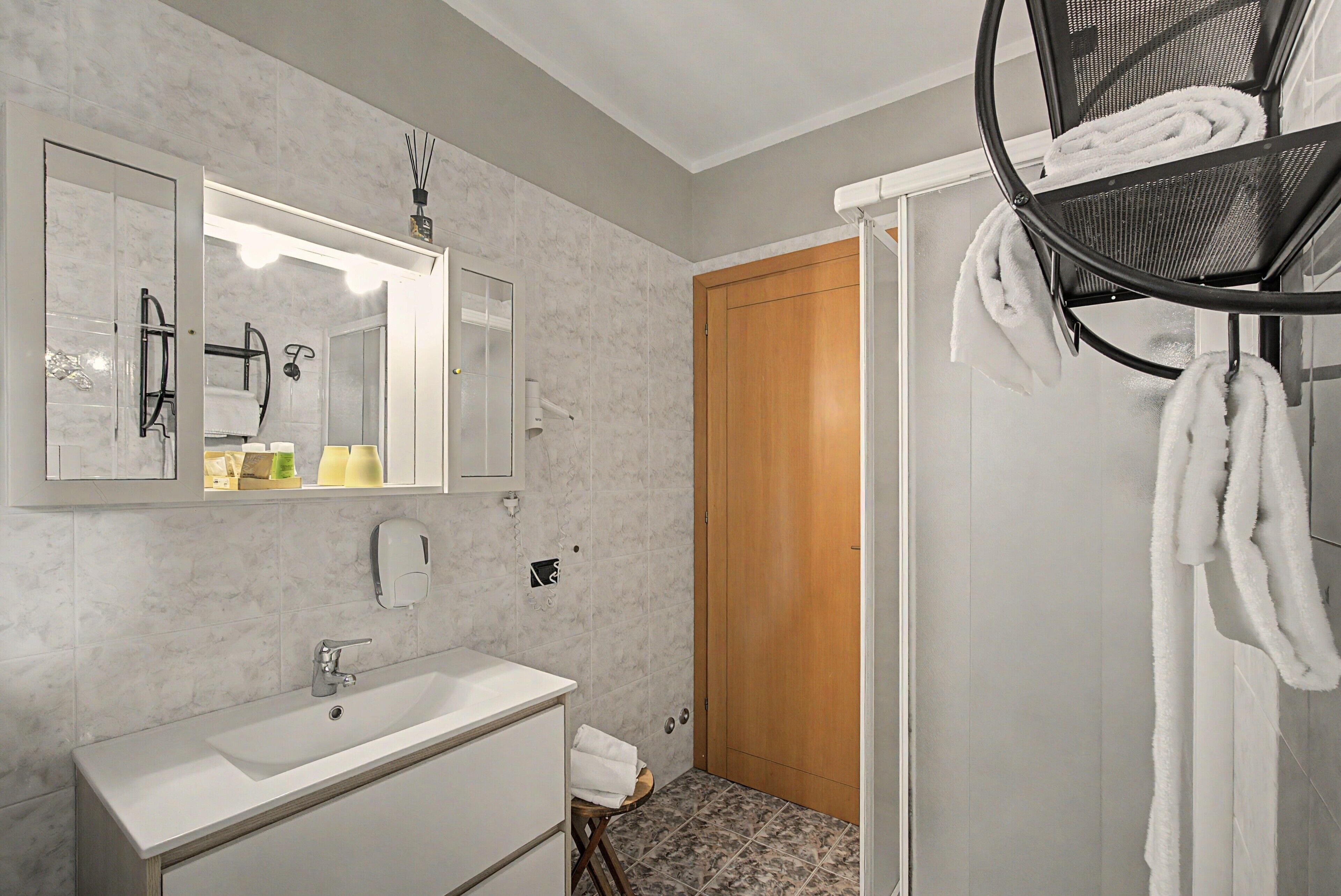 Casa de banho com lavatório branco, espelho e porta-toalhas.