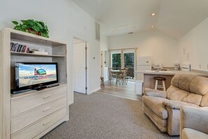 Ein modernes Wohnzimmer mit Fernseher, einer Couch, einem Essbereich und einer Küche.