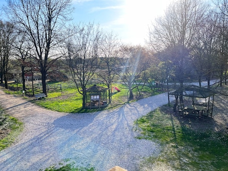 Ein Kiesweg führt zu einer Laube in einem Park mit Bäumen und einer Bank.. Zimmer Papaveri E Papere – Selleria in Caltana