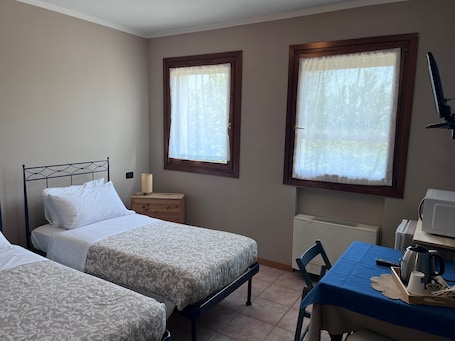 Una camera da letto con due letti, un comodino con una lampada, una scrivania con un bollitore e due finestre con tende.. Camera Papaveri E Papere - Selleria a Caltana