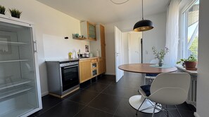 Eine moderne Küche mit Einbauofen, einem Esstisch mit Stühlen und einem Fenster mit Blick.