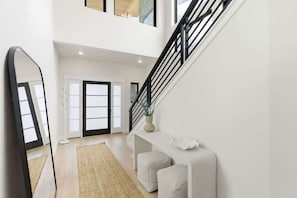 Ein modernes Interieur mit Treppe, Spiegel, Teppich und einer Konsolentisch.