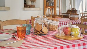Ein Tisch mit karierter Tischdecke, eine Glaserdung mit Keksen, ein Korb und eine Obstauslage.
