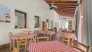 En restaurang med röd- och vitrutiga bordsdukar, trästolar och ett träpanelat tak.