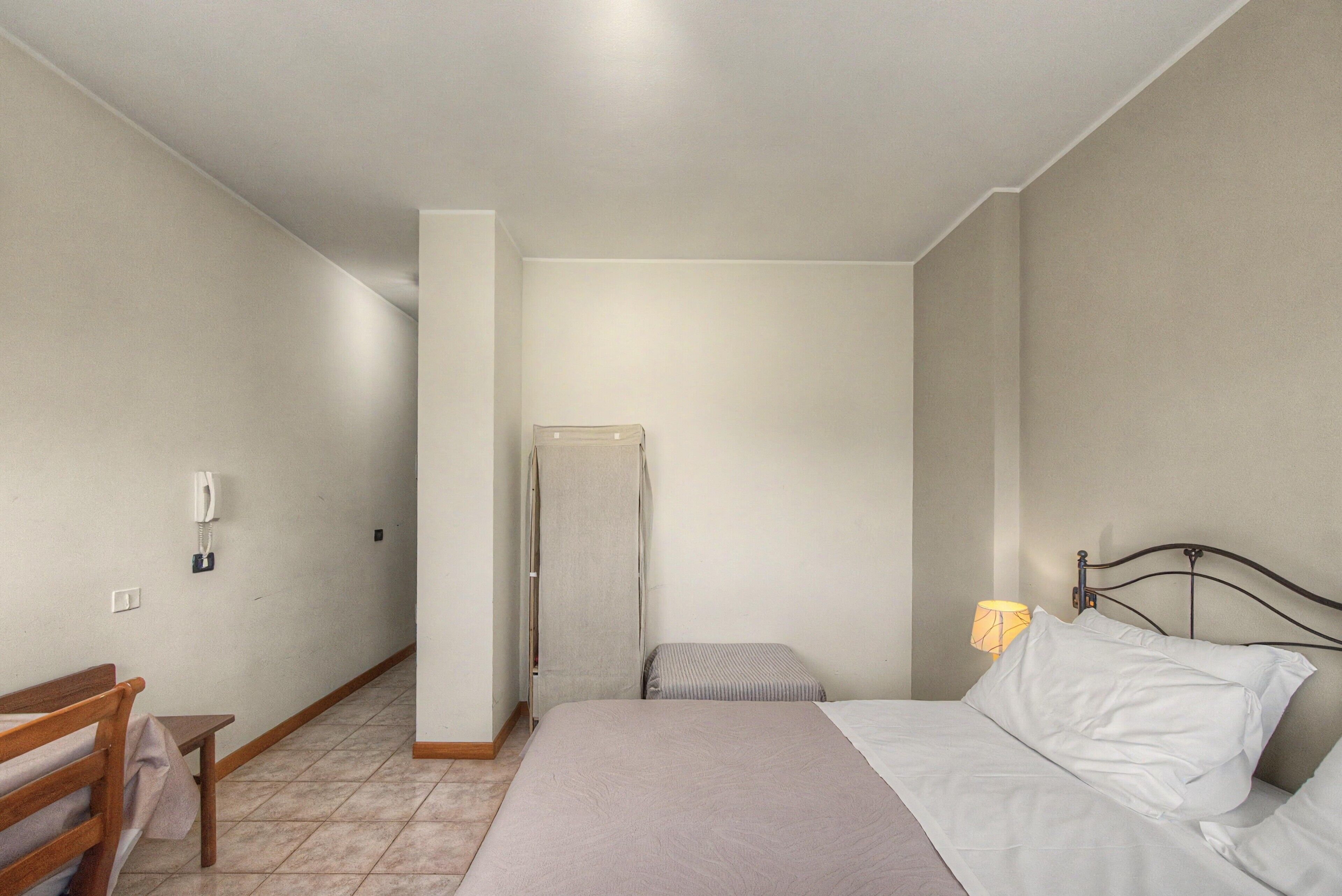 Una camera da letto con un letto, un comodino, una lampada, una sedia e un armadio.
