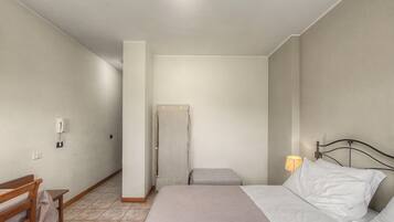 Una camera da letto con un letto, un comodino, una lampada, una sedia e un armadio.