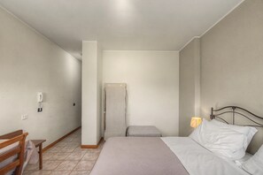Una camera da letto con un letto, un comodino, una lampada, una sedia e un armadio.