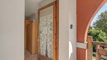 Una porta in legno con un vetrino, una parete bianca e una ringhiera in legno.
