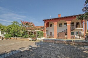 Ein zweistöckiges Gebäude mit Ziegelaußenwand, Rundbogenfenstern und einem Balkon.