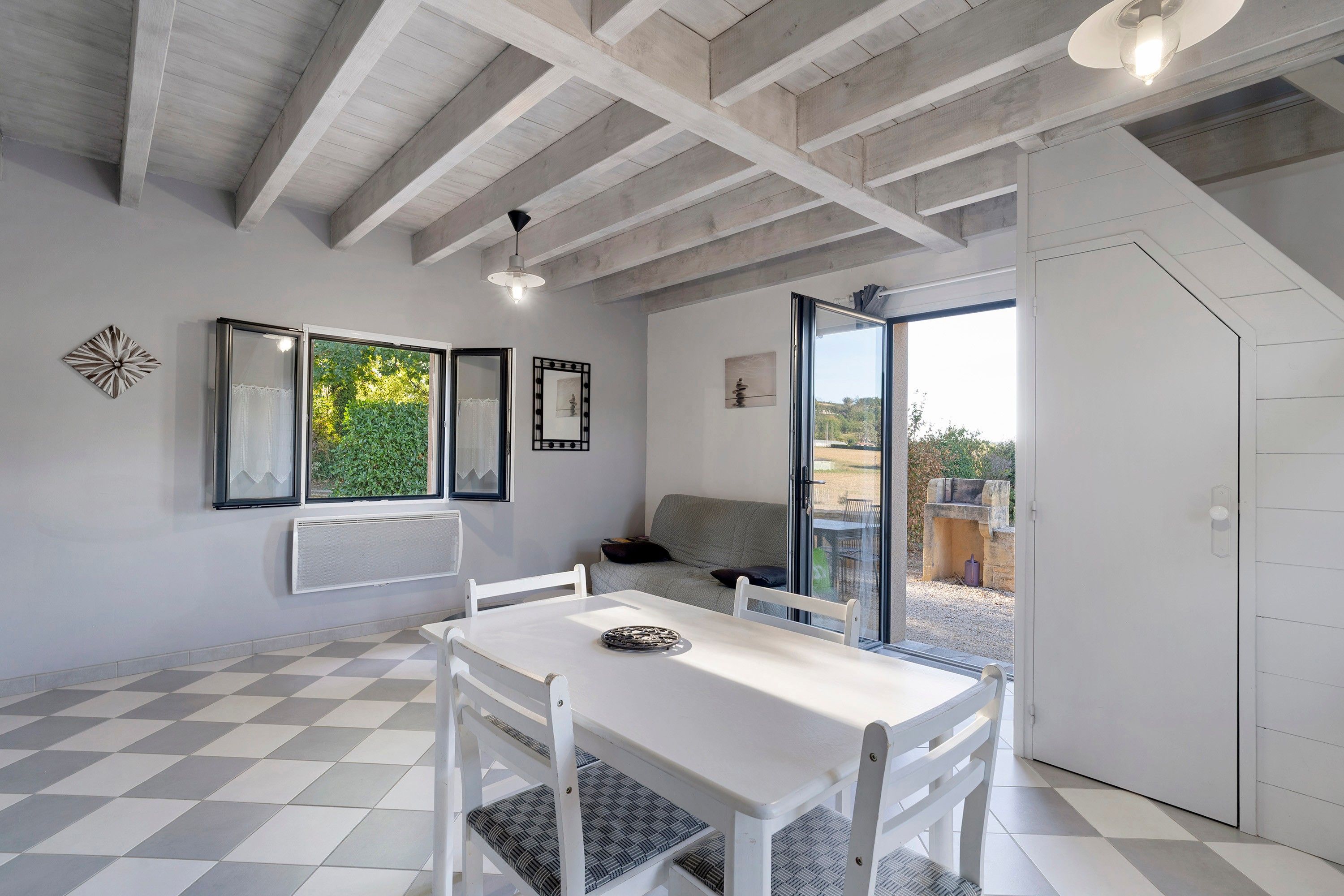 Un interior moderno con piso de cuadros, muebles blancos y un balcón con vistas.