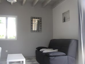 Una habitació amb una taula blanca, un armari fosc, un mirall i un quadre petit a la paret.