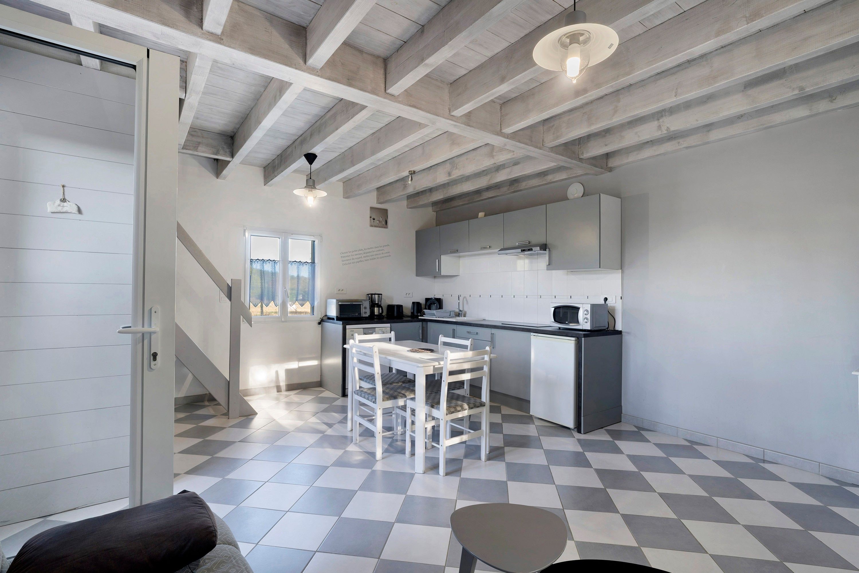 Una cocina moderna con piso a cuadros, armarios blancos y un comedor con mesa y sillas.