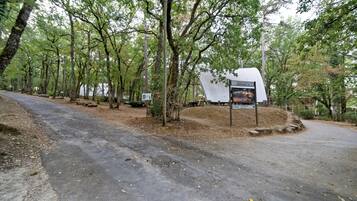 Un área boscosa con un sendero pavimentado que conduce a una estructura blanca con señalización.