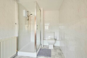 A modern bathroom with a glass-enclosed shower, a toilet, and a radiator. - Host & Stay | Roseberry Avenue (Skegness)