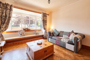 A living room with a sofa, a wooden chest, and a window with curtains. - Host & Stay | Roseberry Avenue (Skegness)