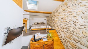 Ein Schlafzimmer mit Etagenbett, Schreibtisch mit Computer, Pflanze und Steinwand.