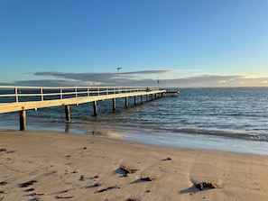 A pier extending into calm waters with a clear sky.