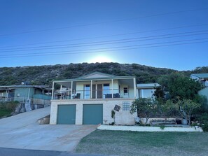 Ein zweistöckiges Haus mit Balkon, Garage und einer Hanglage.