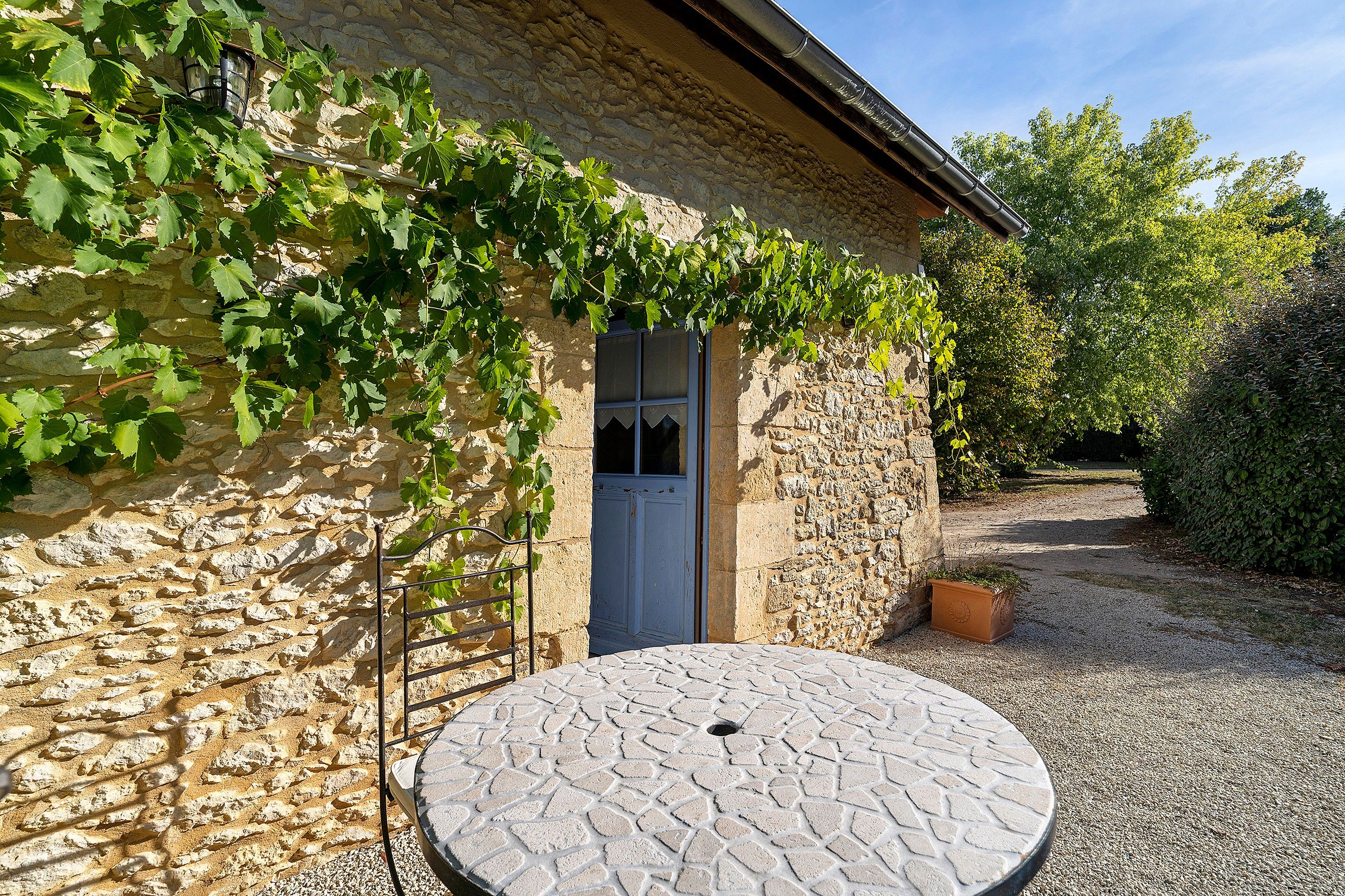 A stone building with a door and a round table in front.
