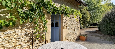 A stone building with a door and a round table in front.