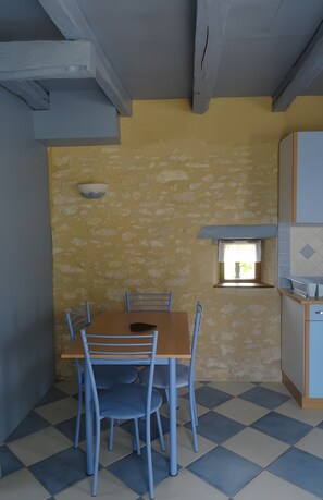 Un comedor con mesa y sillas, una ventana pequeña y una zona de cocina.