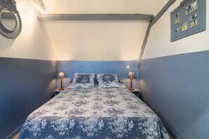 A bedroom with a bed, two bedside lamps, a wall-mounted mirror, and a framed picture. - Charming Restored Small Barn (Montignac-Lascaux)