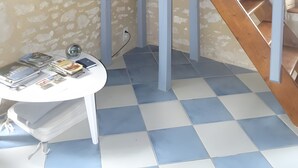 Et værelse med en trætrap, et hvidt bord med magasiner, og et ternet gulv.