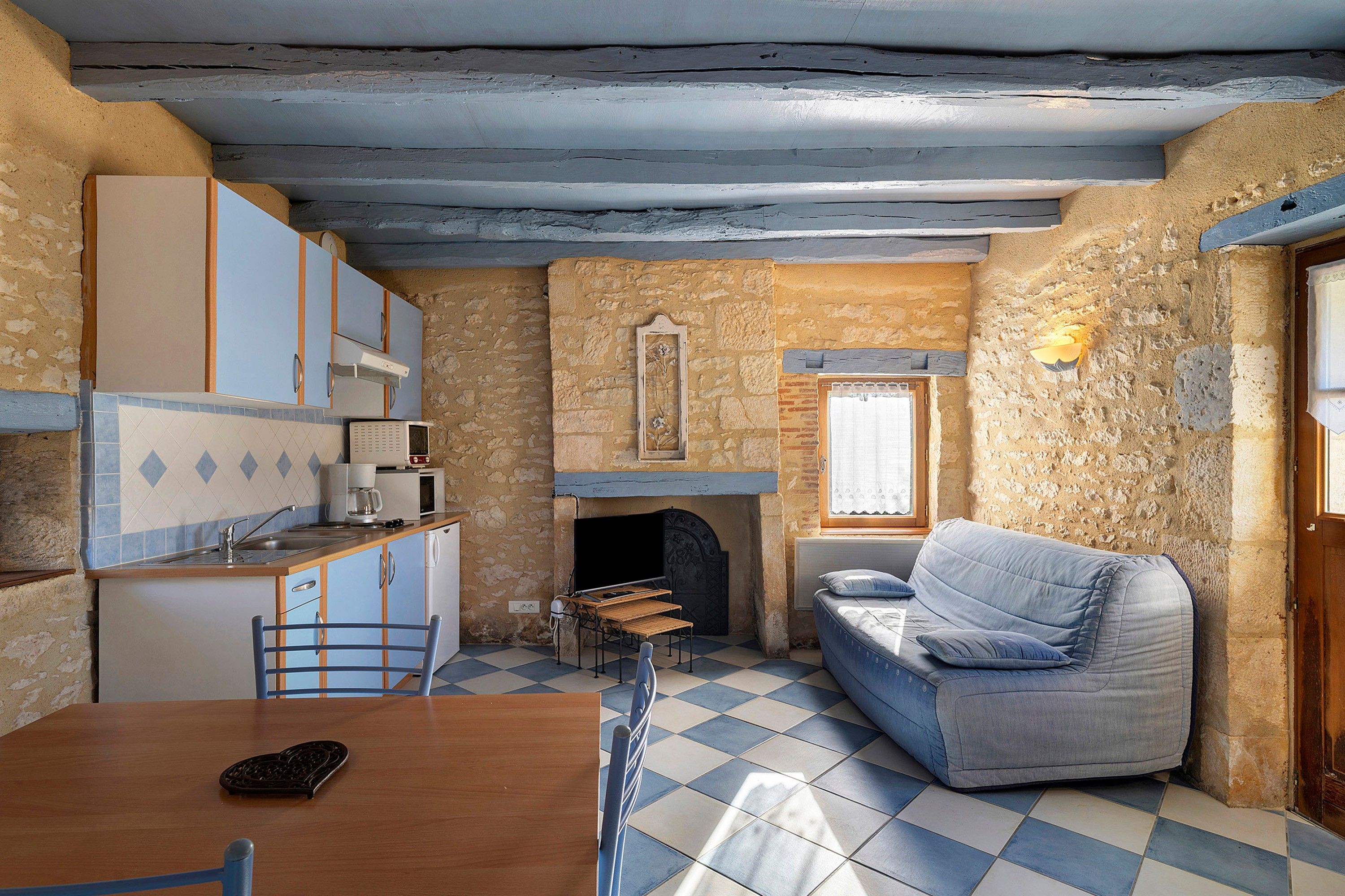 A compact living space with a kitchenette, a dining area, and a seating area with a sofa.