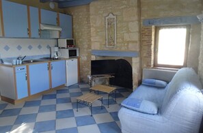 A room with a checkered floor, a kitchenette with blue cabinets, a television, and a sofa. - Charming Restored Small Barn (Montignac-Lascaux)