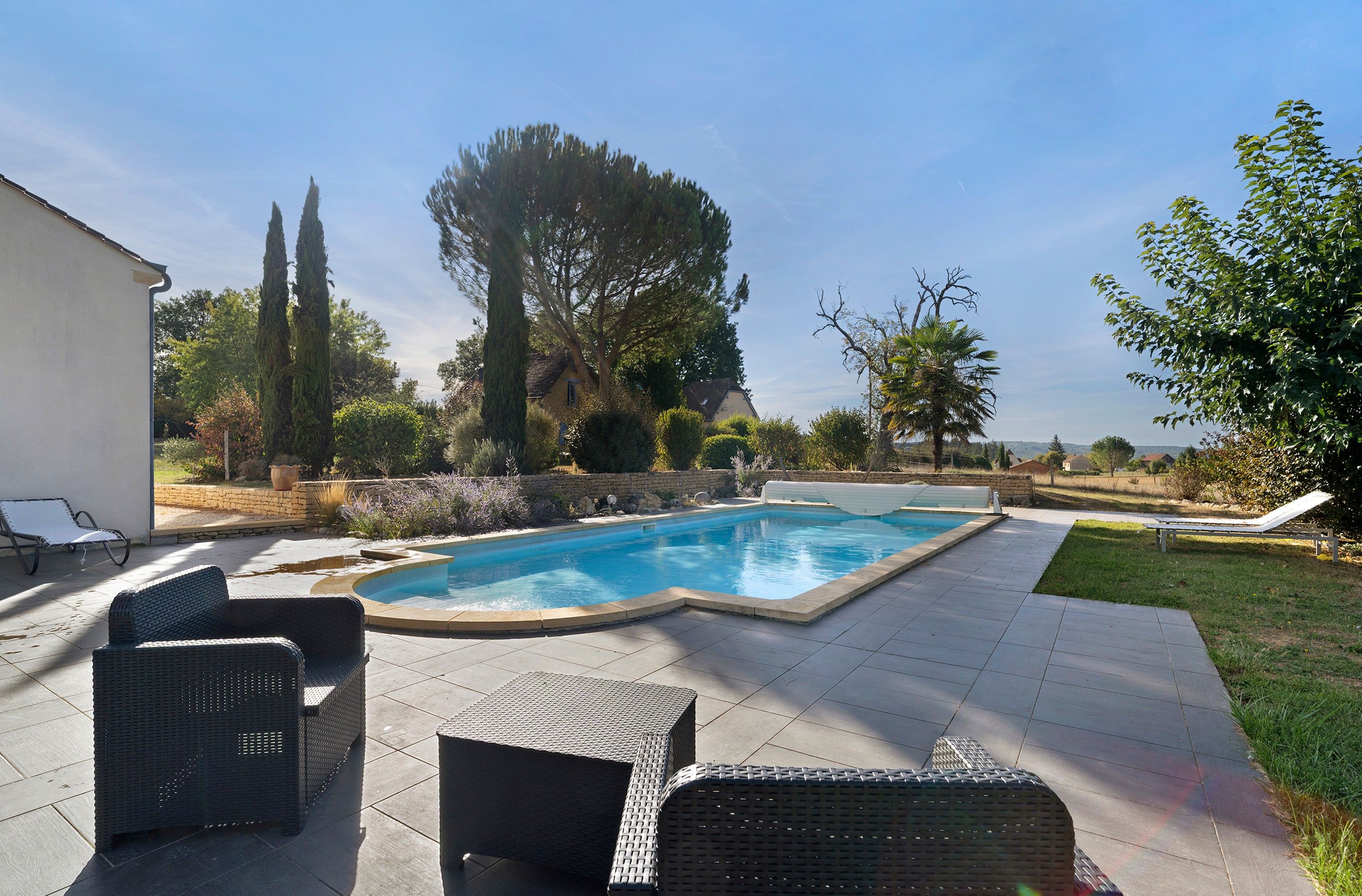 A swimming pool with lounge chairs and a stone wall.