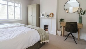 Quarto com cama, guarda-roupa, escrivaninha com cadeira, espelho e lareira.