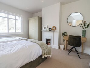 A bedroom with a bed, a wardrobe, a desk with a chair, a mirror, and a fireplace. - 11 Sandhurst Avenue (Lytham St. Anne's)