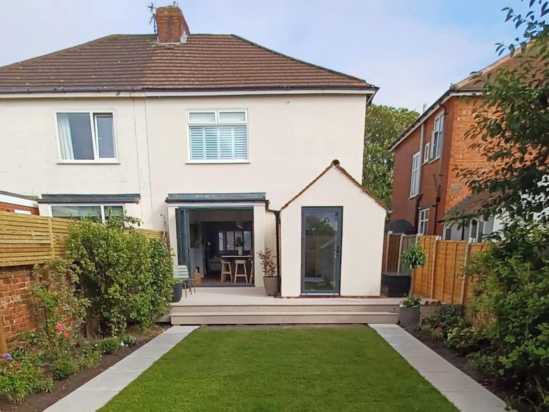 A two-story house with a small attached garage, a front lawn, and a wooden fence.