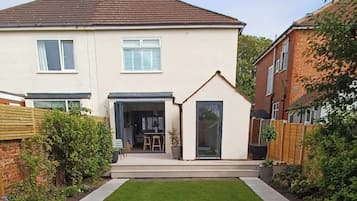 A two-story house with a small attached garage, a front lawn, and a wooden fence.