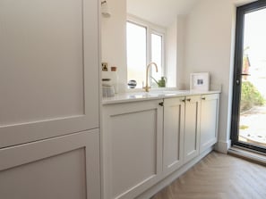 Eine Küche mit weißen Schränken, einem Fenster und einer Spüle.