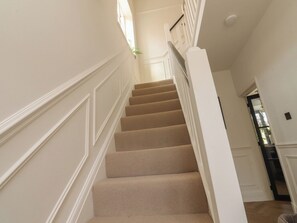 Eine Treppe mit beige gefärbten Stufen, weißen Wänden und einem weißen Geländer.