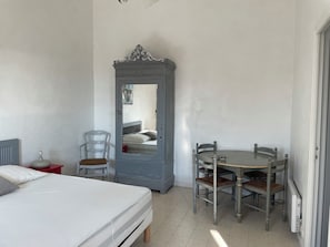 Ein Schlafzimmer mit Bett, Sessel, Tisch und Kleiderschrank.