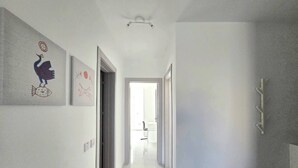 A hallway with a ceiling fan, a door leading to a bright room, and a wall-mounted rack. - 3 bedroom, 2 bathroom Brand new Apartment in Central Gozo (Ir-Rabat Għawdex)